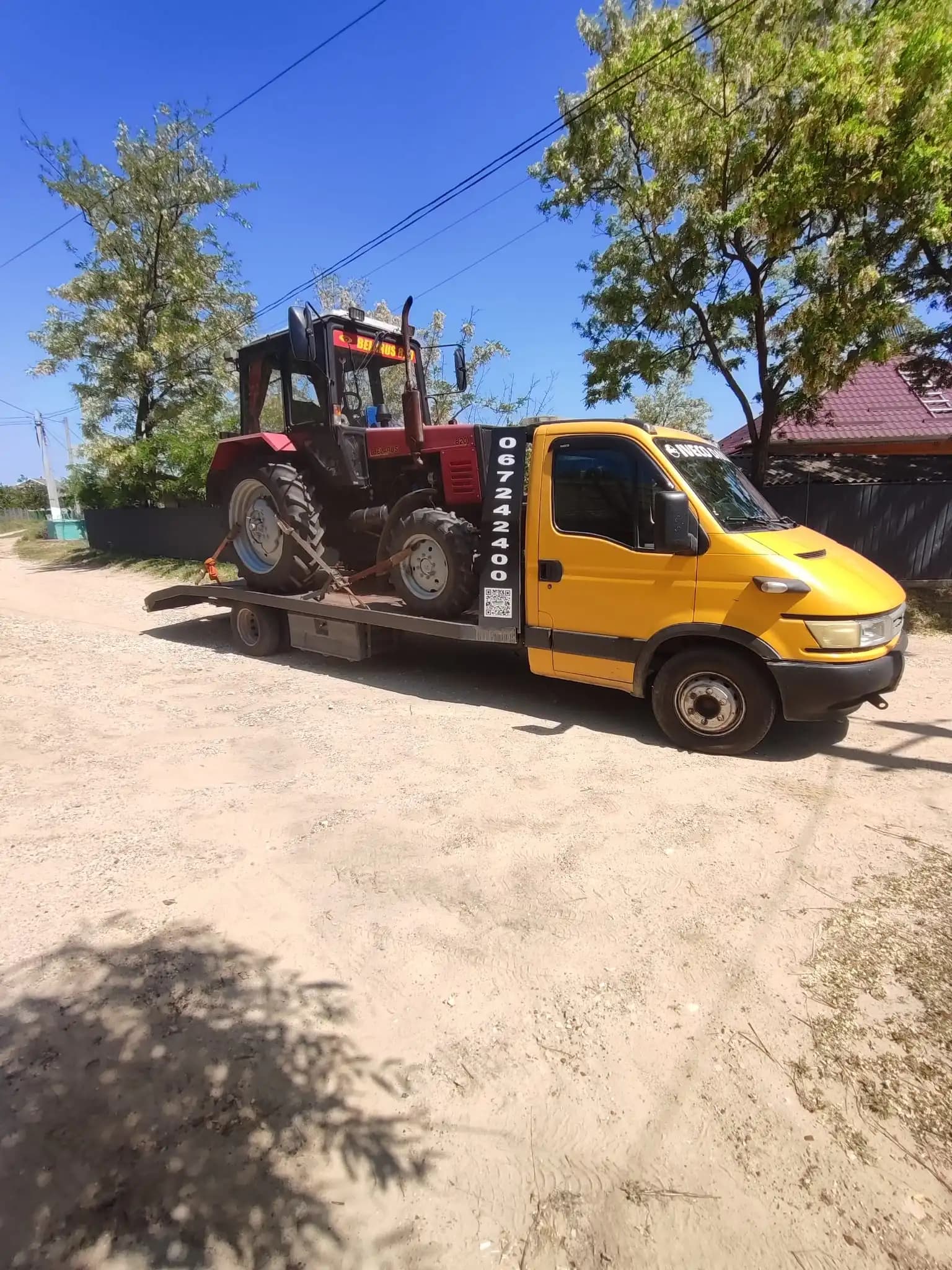 Evacuator auto transportând tractor agricol pe platformă în Chișinău, intervenție non-stop